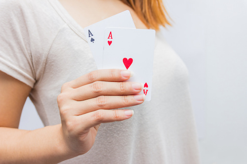 young woman holding in hand poker card with combination of Full House. in focus hand and poker card.